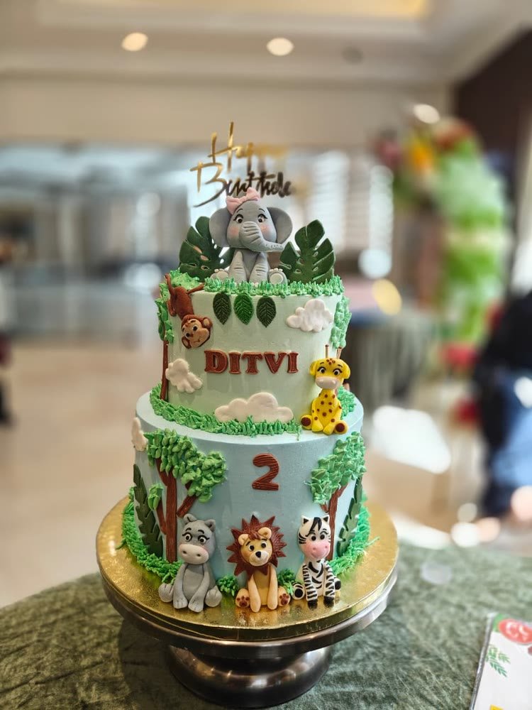 Two-tier jungle-theme birthday cake with fondant elephant, lion, zebra and giraffe